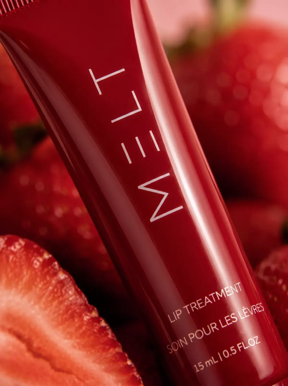 A close frame of the MELT logo on the red tube against cut strawberries.